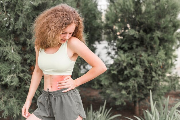 Slanke jonge vrouw die tailleverwonding bekijkt