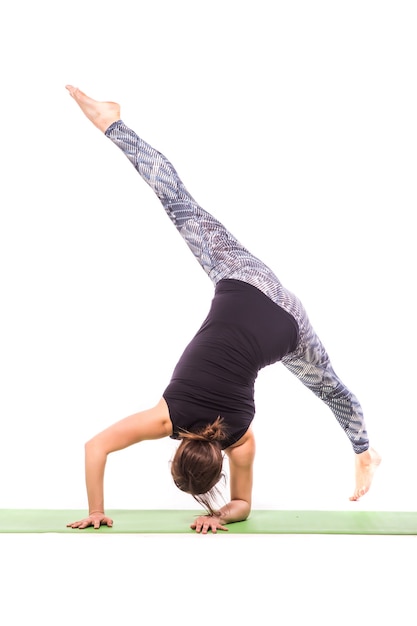 Slanke jonge vrouw die yogaoefening doet. Geïsoleerd op witte achtergrond.