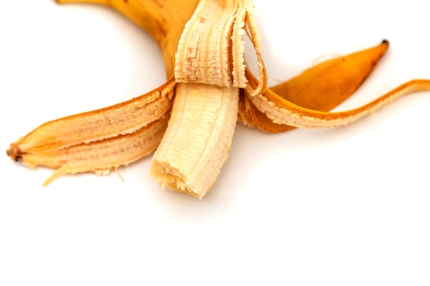 Slechte gebeten banaan die op witte achtergrond wordt geïsoleerd. oude gepelde banaan. tropisch geel fruit. selectieve aandacht. concept van goede voeding. plaats voor een inscriptie of logo Premium Foto