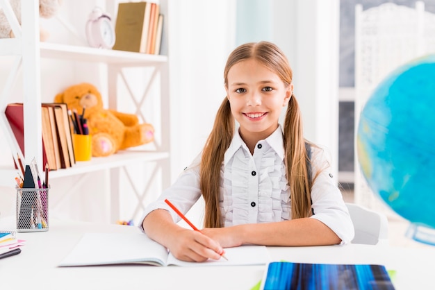 Slim schoolmeisje zit aan bureau