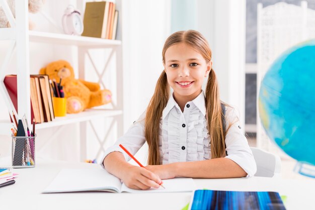 Slim schoolmeisje zit aan bureau