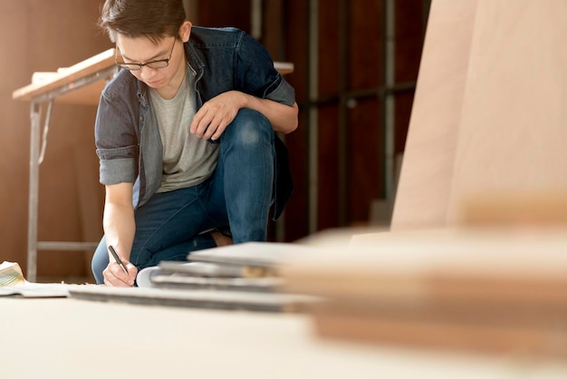 Slimme aantrekkelijke bril mannelijke casual kostuum aannemer houtwerk op site huis renovatie concept glimlach en zelfverzekerde timmerman aannemer op site bouw achtergrond