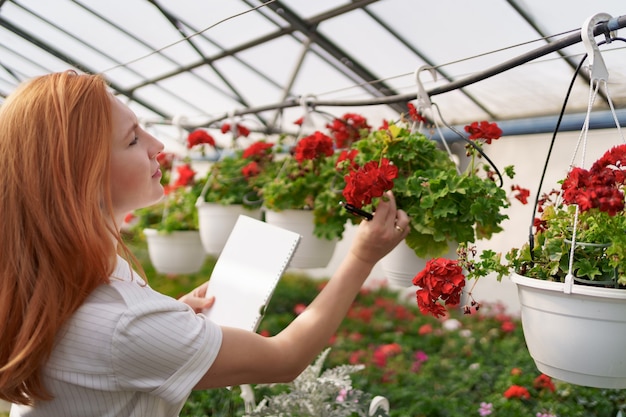 Slimme kassturing. werkneemster inspecteert rode bloemen en noteert gegevens bij daglicht