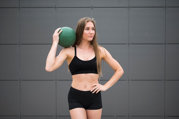 Gratis foto slimme kijkende vrouw die een bal middelgroot schot houdt