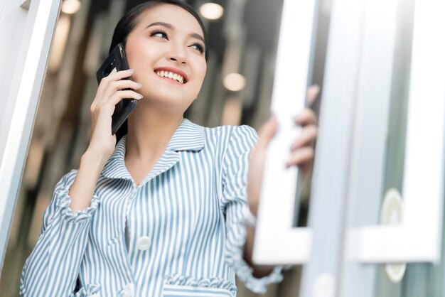 Slimme mooie aantrekkelijke Aziatische vrouw lonh haar glimlach hand houden smartphone communicatie sociaal aansluiten ideeën concept wit vervagen bokeh achtergrond