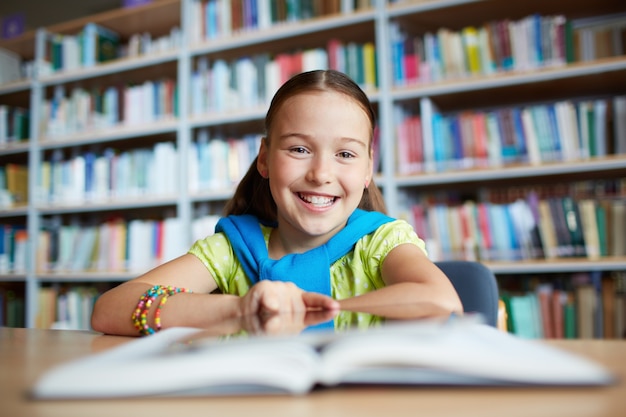 Gratis foto slimme schoolmeisje zit in de bibliotheek