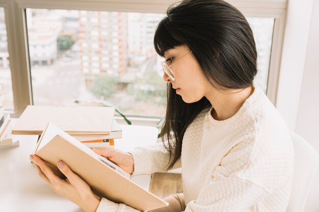 Slimme vrouw die aan tafel leest