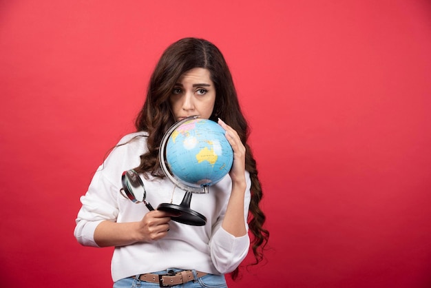 Slimme vrouw poseren met globe en vergrootglas. Hoge kwaliteit foto