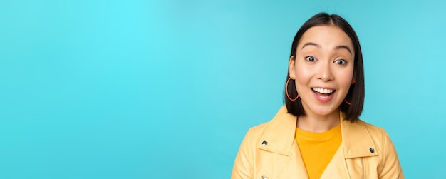 Sluit het portret van een natuurlijk Aziatisch meisje dat lacht en lacht en er gelukkig uitziet terwijl ze over een blauwe achtergrond staat