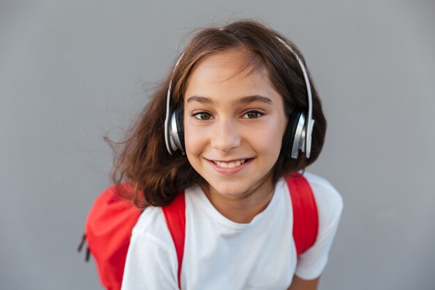 Sluit omhoog beeld van gelukkige donkerbruine schoolmeisje het luisteren muziek