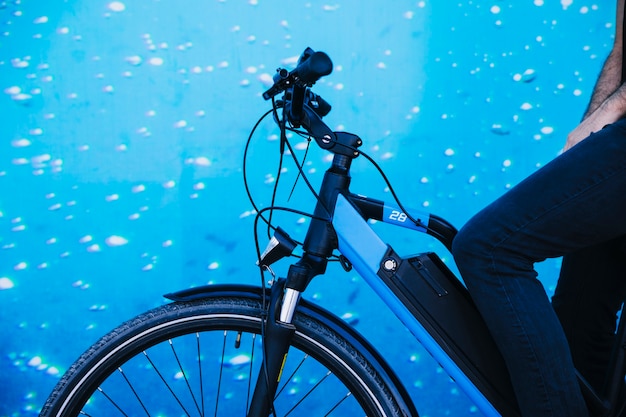 Sluit omhoog fietser op e-fiets met aquariumachtergrond