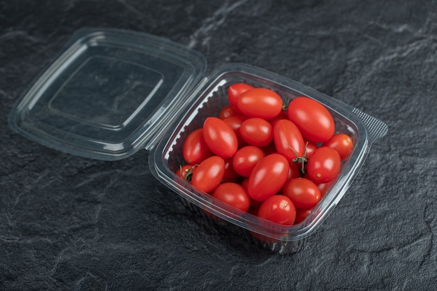 Gratis foto sluit omhoog foto van kleine rode tomaten in plastic container op zwarte container. hoge kwaliteit foto