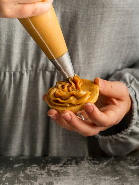 Sluit omhoog handen die alfajores met room voorbereiden