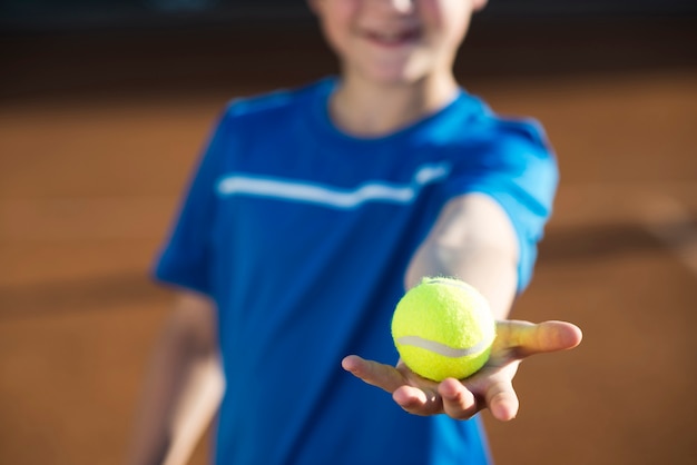 Sluit omhoog jong geitje die een tennisbal in hand houden