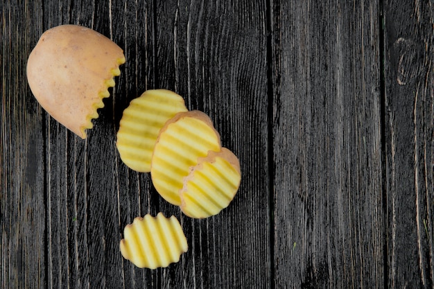 Sluit omhoog mening van gesneden en gesneden aardappelplakken op houten achtergrond met exemplaarruimte