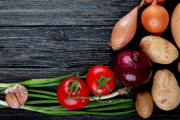 Sluit omhoog mening van groenten als de tomatenaardappel en ui van de knoflooksjalot op houten achtergrond met exemplaarruimte