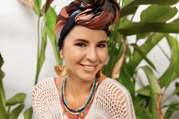 Sluit omhoog portret van lachende vrouw met een tulband bij het hoofd stellen over palmen