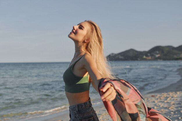 Sluit omhoog portret van mooie blonde Europese vrouw die op het strand lopen.