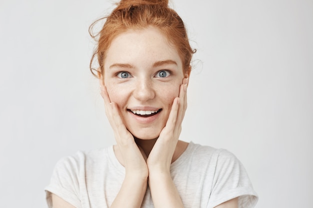 Sluit omhoog portret van verraste gelukkige gembervrouw met en sproeten. Moties op wit.