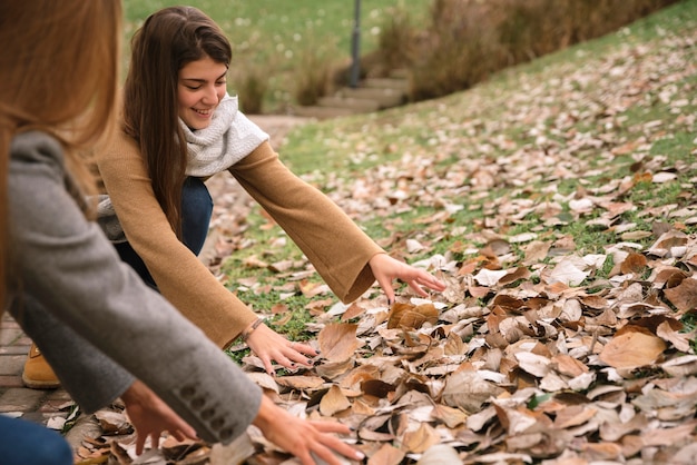 Gratis foto sluit omhoog twee vrouwen speel met bladeren in het park