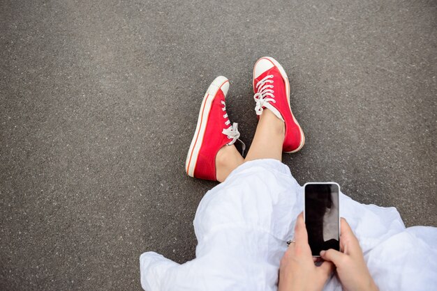 Sluit omhoog van benen in rode keds liggend op asfalt.