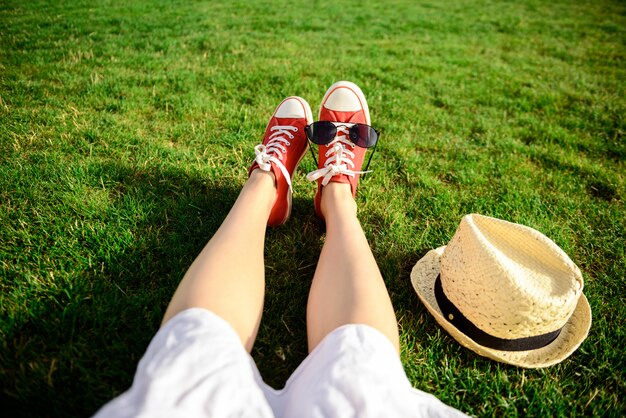 Sluit omhoog van benen in rode keds liggend op gras.