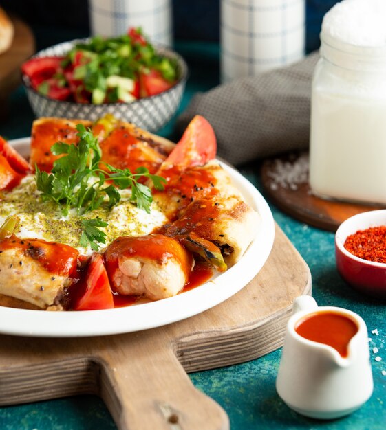 Sluit omhoog van beytikebab met rundvlees dat in flatbread wordt verpakt die met tomatensaus wordt gediend