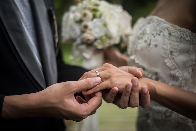 Sluit omhoog van bruidegom draagt ​​de ringsbruid in huwelijksdag. Liefde, gelukkig huwelijkconcept.