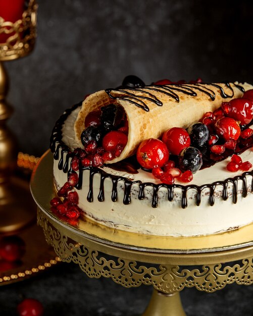 Sluit omhoog van chocolade druipende cake die met verpakte wafel met bessen wordt bedekt