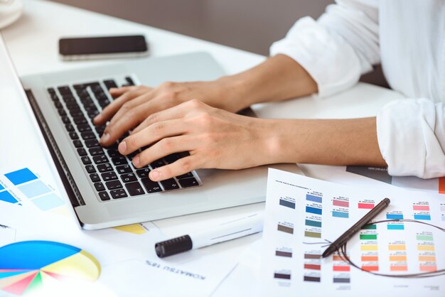 Sluit omhoog van de handen van de onderneemster typend op laptop bij werkplaats.