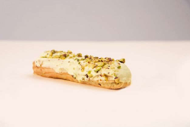 Sluit omhoog van eclair met witte room en noten die over wit wordt geïsoleerd