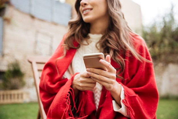 Sluit omhoog van een glimlachende vrouw die mobiele telefoon houdt