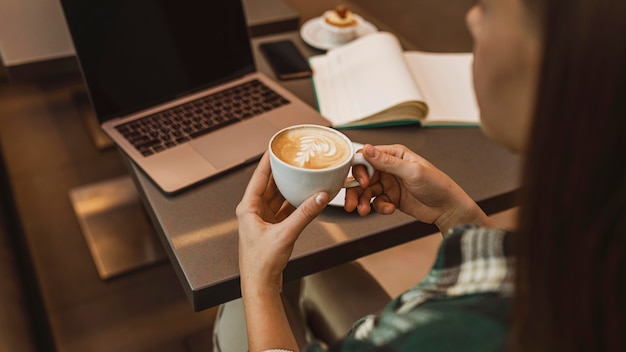 Sluit omhoog van een vrouw die van een koffiekop geniet