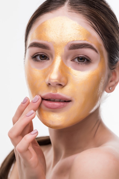 Sluit omhoog van gezonde jonge vrouw met gouden kosmetisch gezichtsmasker op zachte huid.
