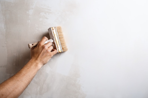 Sluit omhoog van hand het schilderen muur met borstel.