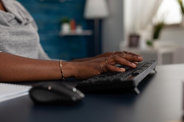 Sluit omhoog van handen die toetsenbord gebruiken om aan computer aan bureau te werken. Jonge vrouw die aan een zakelijk project werkt met modern apparaat en technologie thuis, surfend op online internetwebsite.