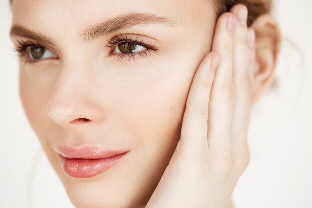 Sluit omhoog van jong mooi meisje glimlachend wat betreft gezicht. Spa schoonheid gezondheid en cosmetologie concept.