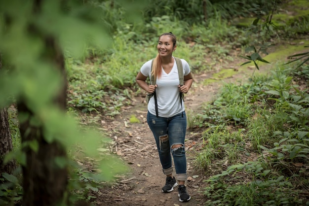 Sluit omhoog van jonge backpacker lopend door het bos gelukkig met aard. Reis concept.