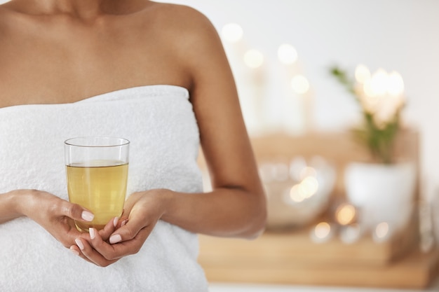 Sluit omhoog van jonge vrouw in het glas van de handdoekholding met groene thee in kuuroordsalon.