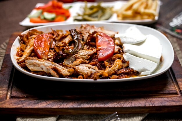 Sluit omhoog van kippenkebab met tomatensaus die met de groenten in het zuur en de groenten van yoghurtgebraden gerechten wordt gediend