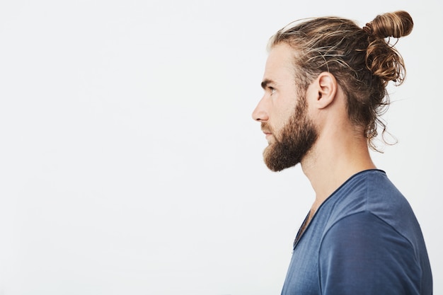 Sluit omhoog van knappe gebaarde hipsterkerel met haar in broodje