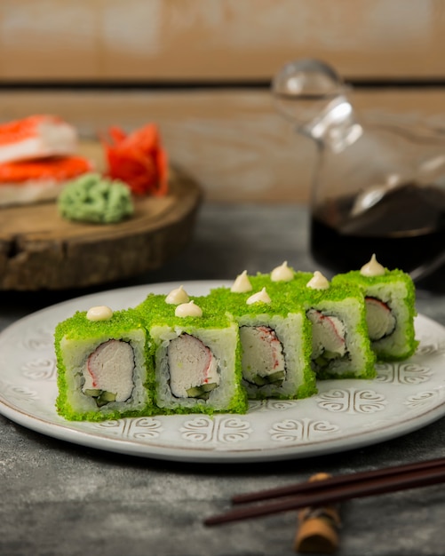 Sluit omhoog van sushi met krabstokken worden geplaatst, komkommer, in groene tobiko worden behandeld die