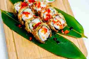Gratis foto sluit omhoog van sushibroodjes die met rode tobiko worden versierd die op bladeren wordt gediend
