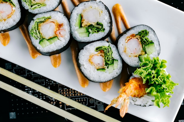 Sluit omhoog van sushibroodjes met tempurakomkommer en sla