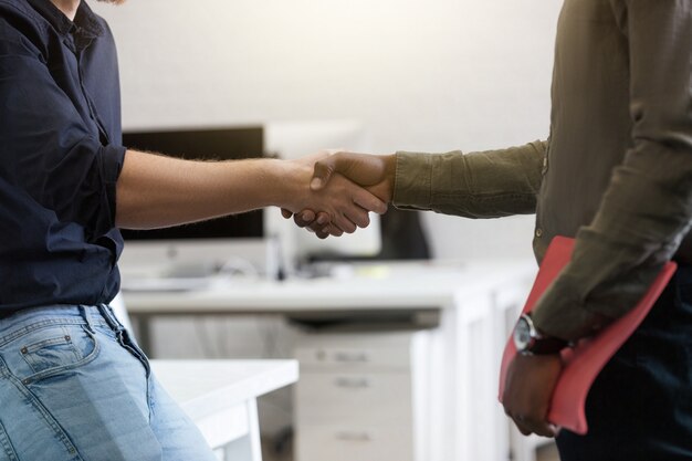 Sluit omhoog van twee jonge collega's die handen schudden