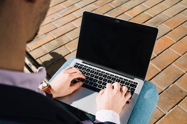 Sluit omhoog van zakenman die laptop in openlucht met behulp van