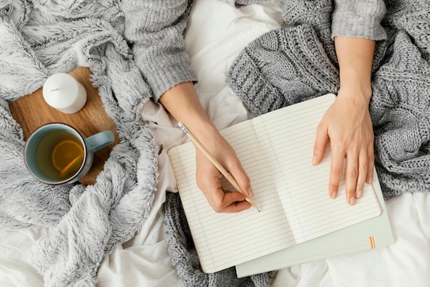 Sluit omhoog vrouw die in notitieboekje schrijft