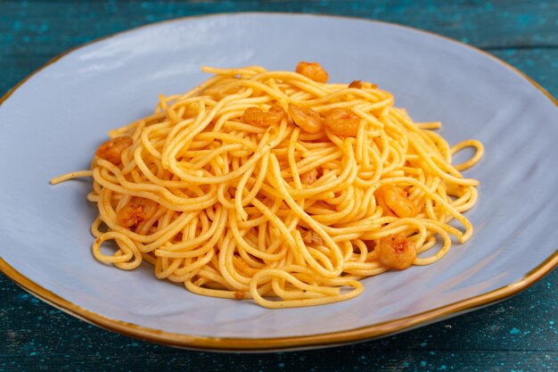 Sluit vooraanzicht gekookte Italiaanse pasta lekker in blauw bord op blauw hout