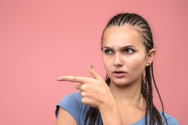 Sluit vooraanzicht van jong meisje wijzend met ernstig gezicht op roze