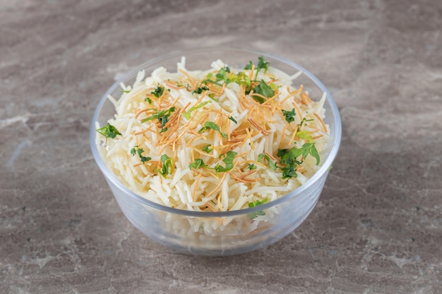 Smaakvolle vermicelli pasta met groene groente in de kom, op het marmer.